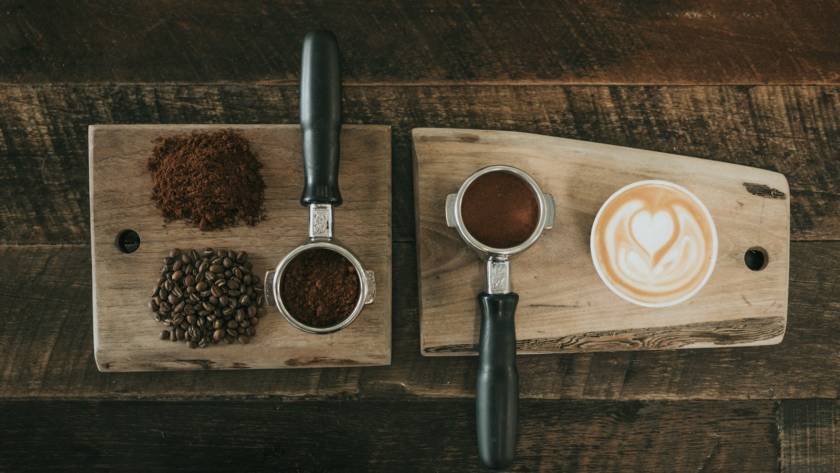 coffee beans beside coffee powder on brown wooden board