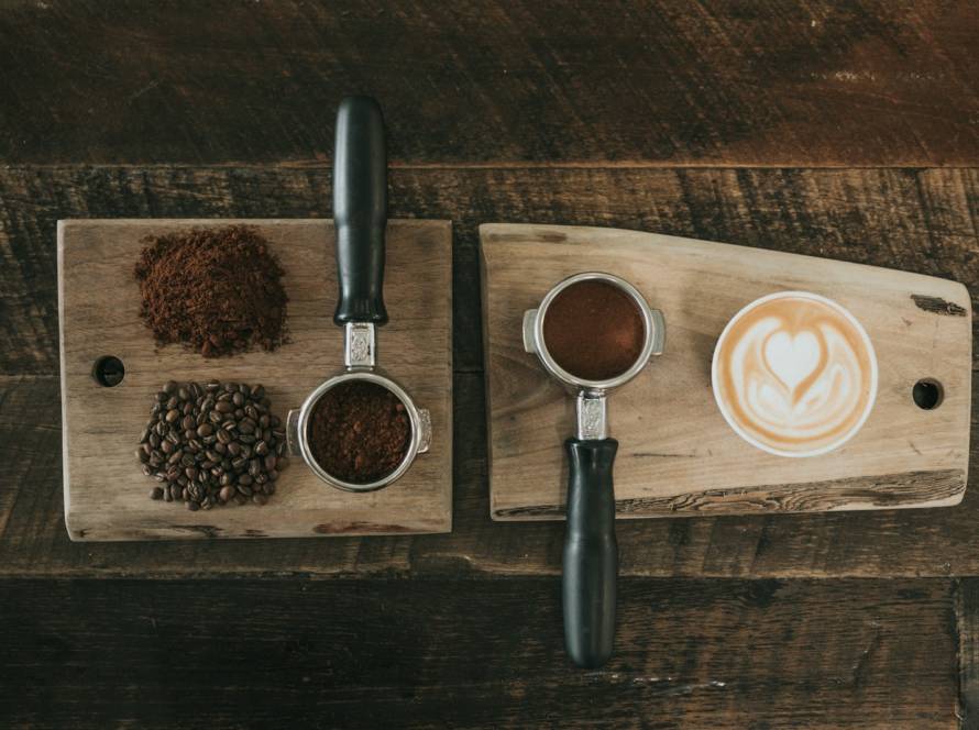 coffee beans beside coffee powder on brown wooden board